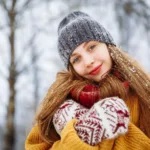 femeie tanara aflata afara pe timp de iarna, cu un ten luminos si zambind
