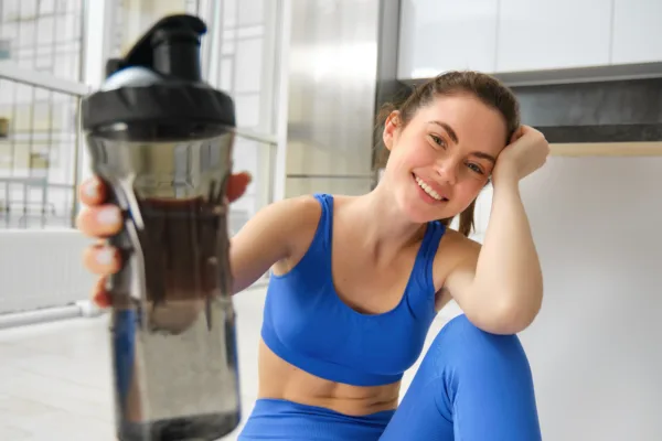 femeie la sala de fitness consumand cafea